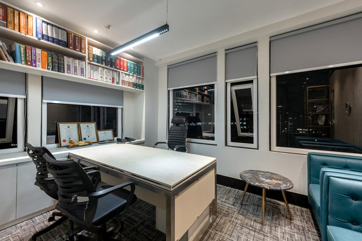 Modern office with desk chairs and bookshelves near windows.